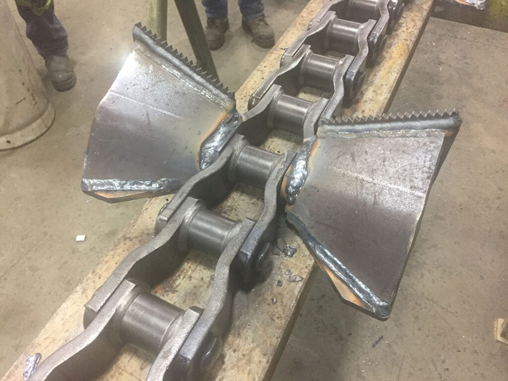 Chaîne industrielle avec palettes métalliques fabriquées et soudées sur mesure