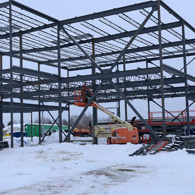 Structure d’acier en cours d’installation sur un chantier commercial en hiver